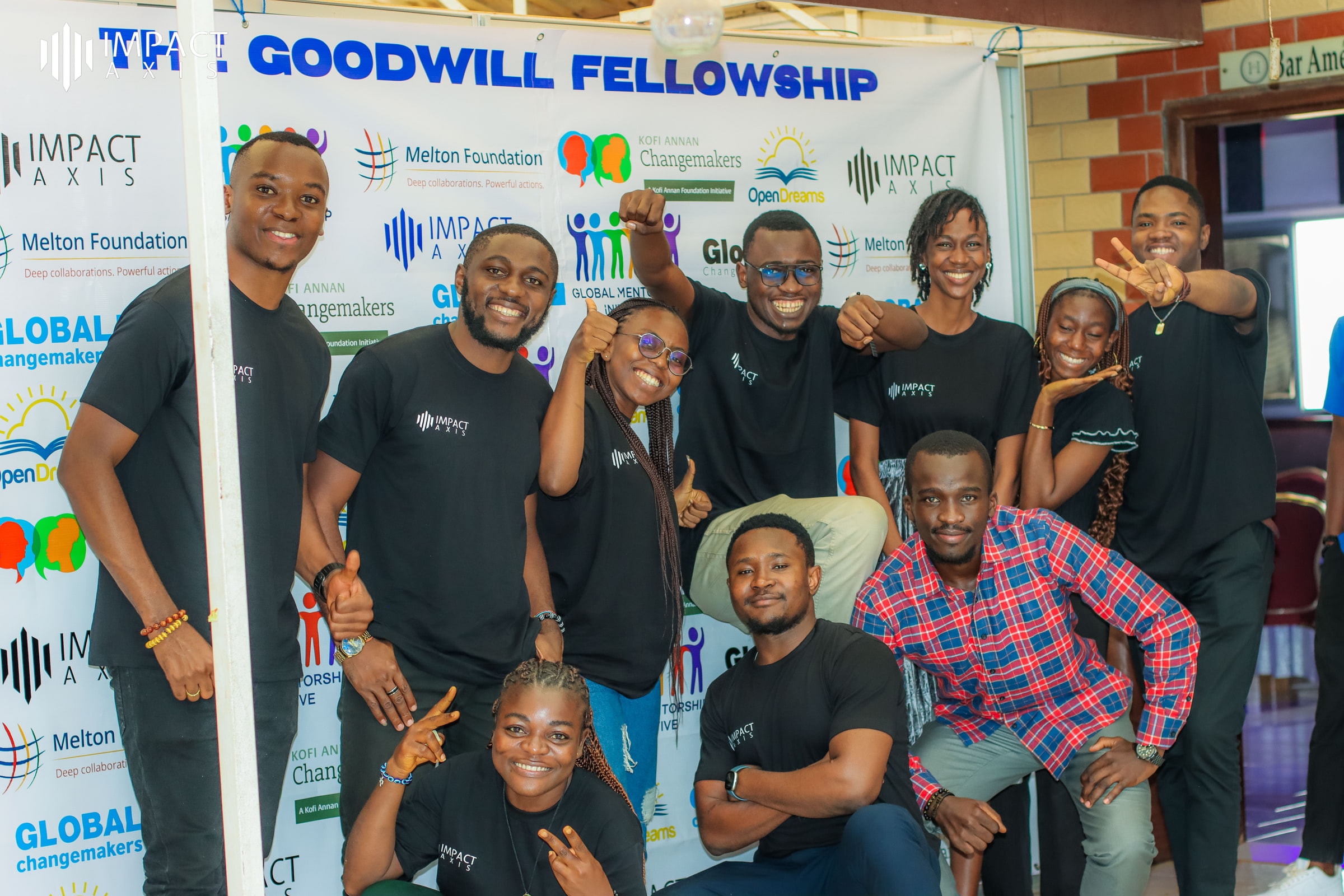 Des participants de la Goodwill Fellowship en T-shirts noirs Impact Axis posent ensemble devant la bannière du programme